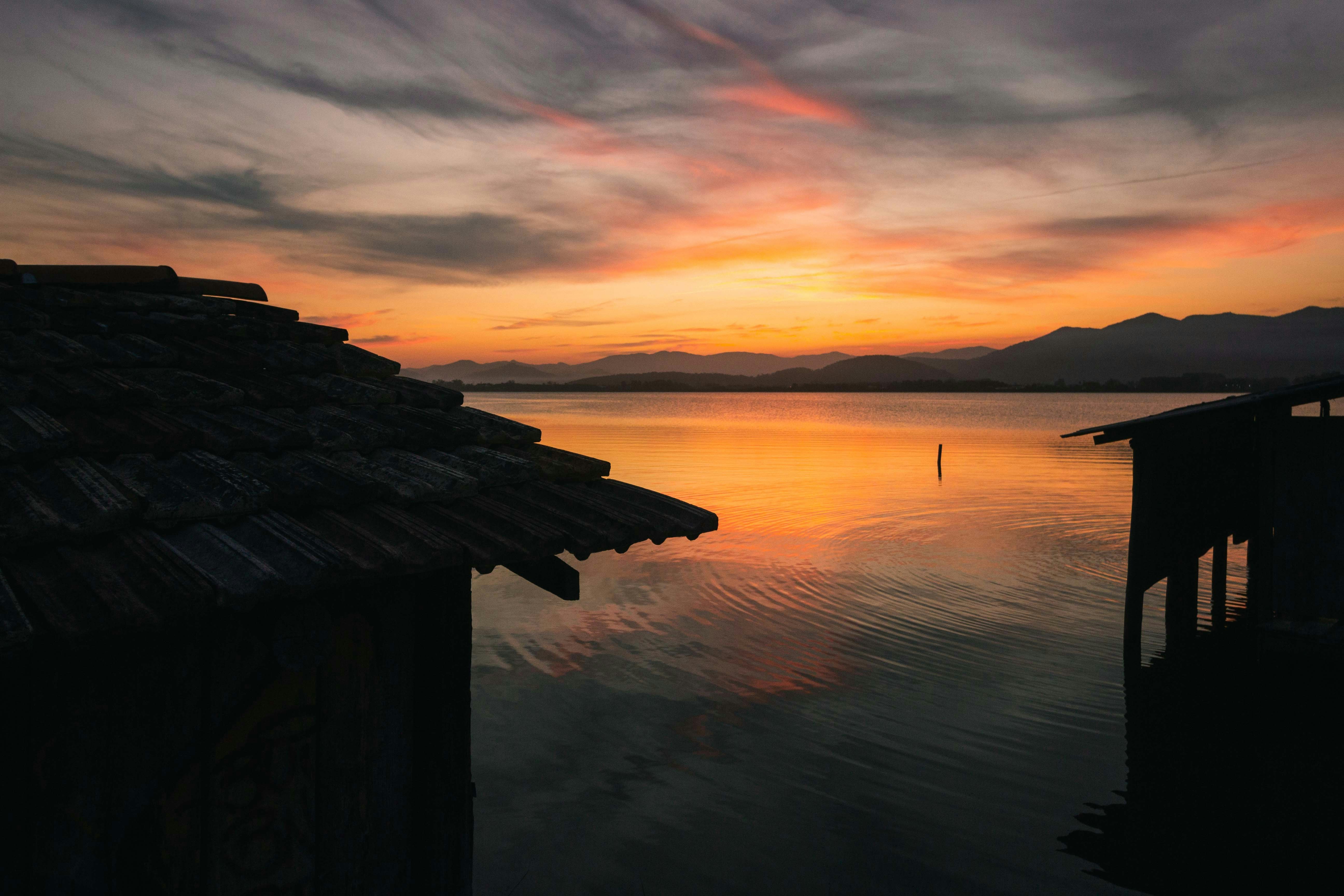 brown wooden dock on body of water during sunset